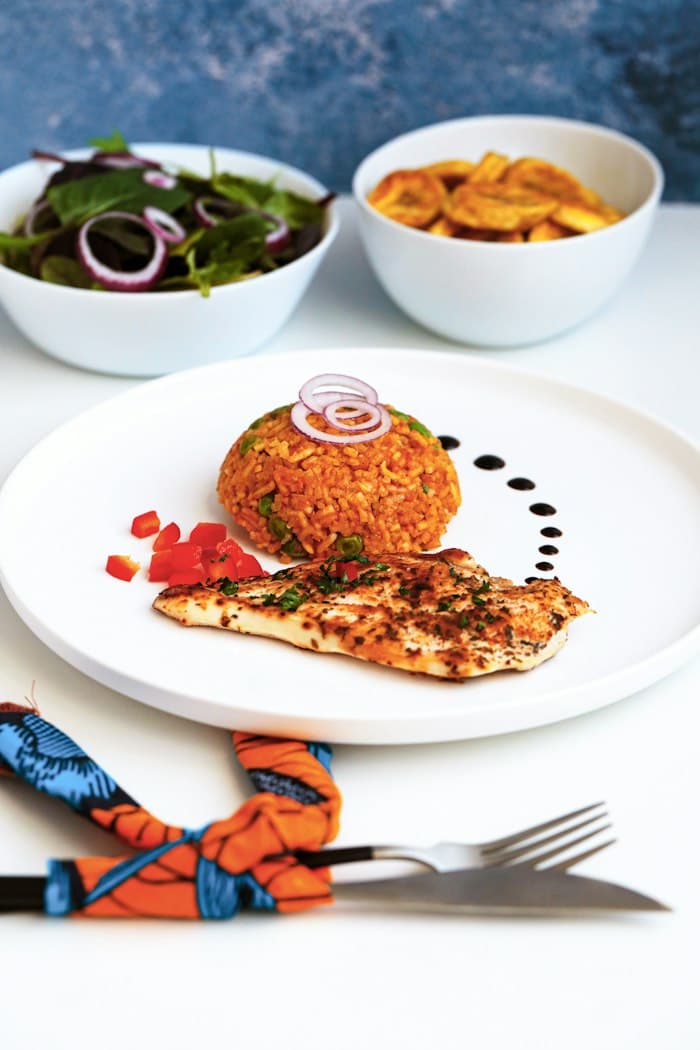 A freshly prepared plate of jollof rice and grilled chicken